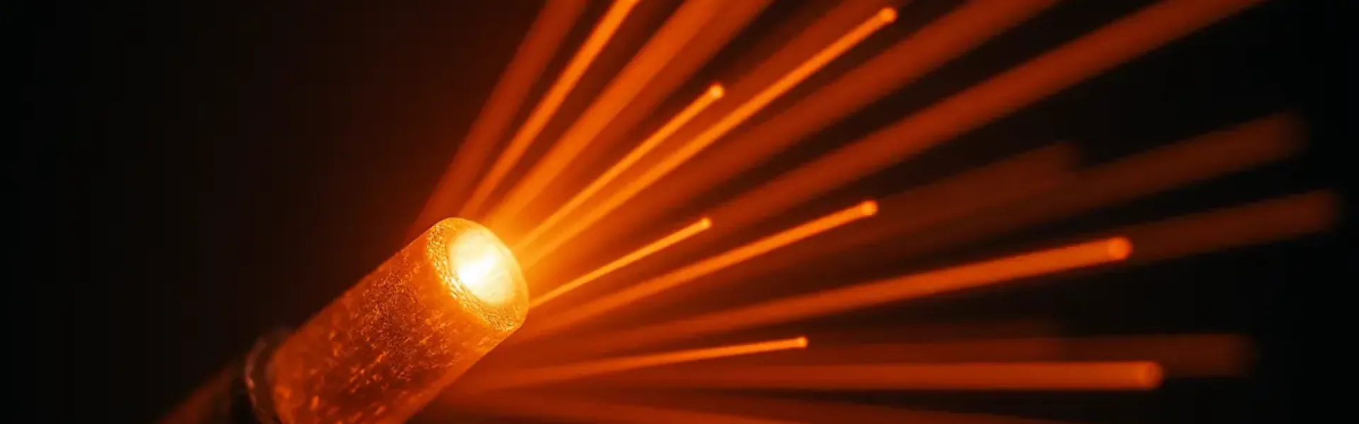 Nahaufnahme eines leuchtenden Glasfaserkabels mit ausstrahlenden Lichtstrahlen.